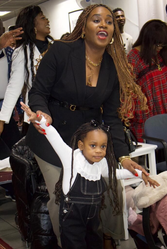A woman and a young girl participating enthusiastically in a worship service at Église La Bonne Semence.