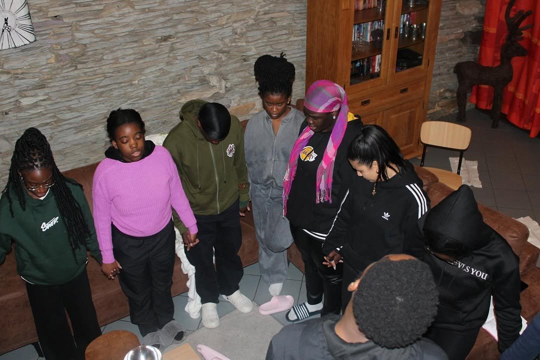Group of young adults holding hands in a circle indoors