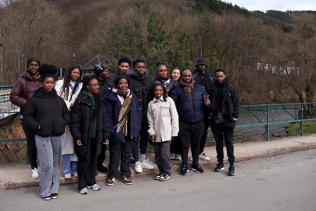 Group of fourteen diverse people standing on a bridge in a natural setting