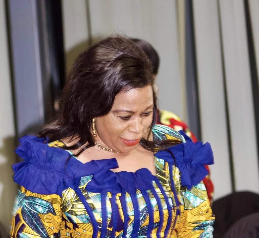 Woman in traditional African attire with vibrant yellow and blue patterns at Église La Bonne Semence