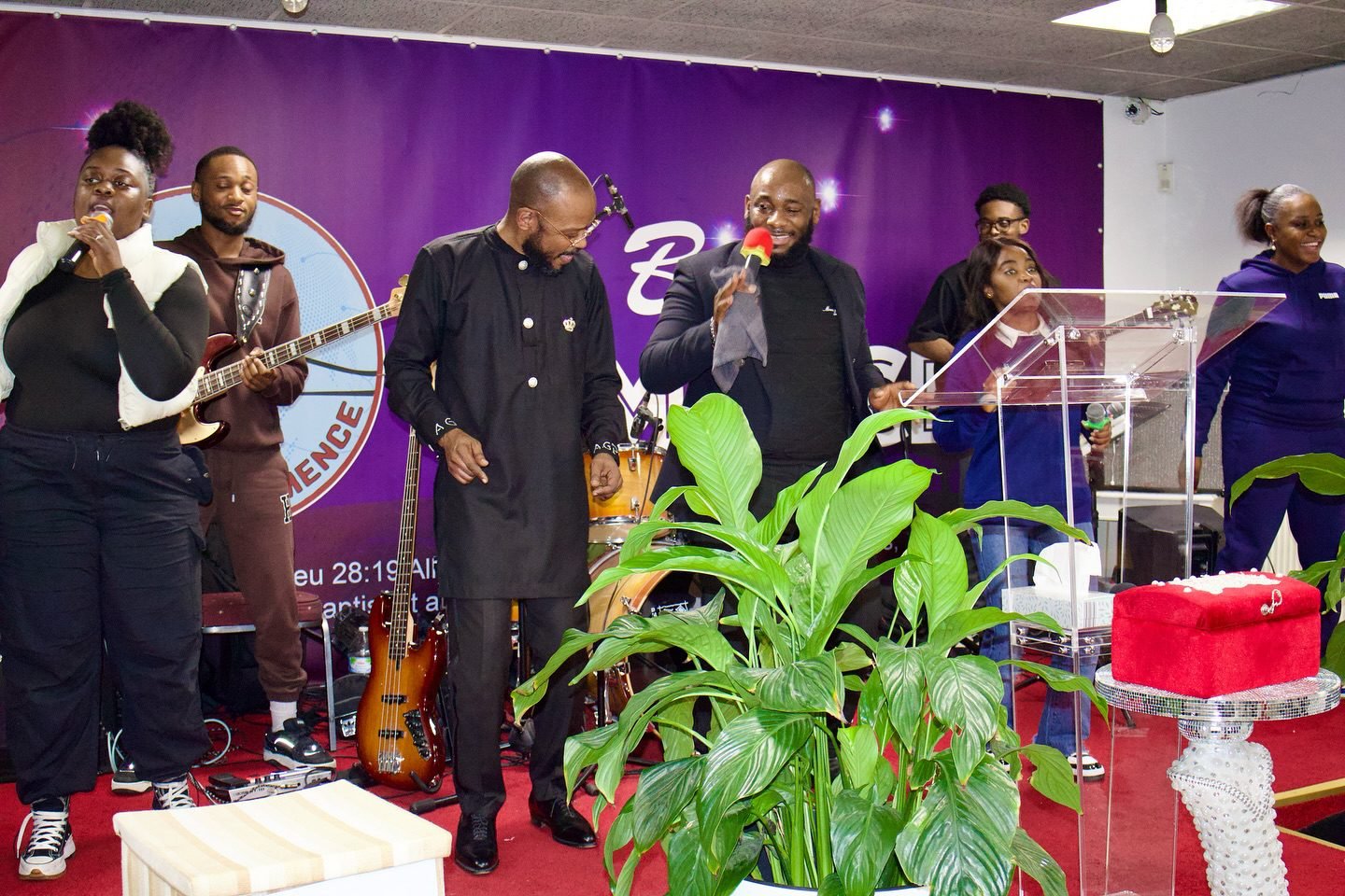 Church leaders and musicians performing at Église La Bonne Semence, with a woman singing into a microphone