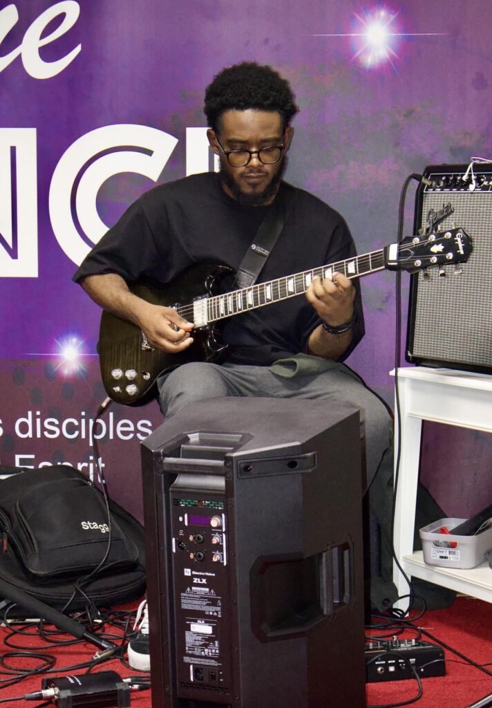 tarist playing an electric guitar during a church service at Église La Bonne Semence.