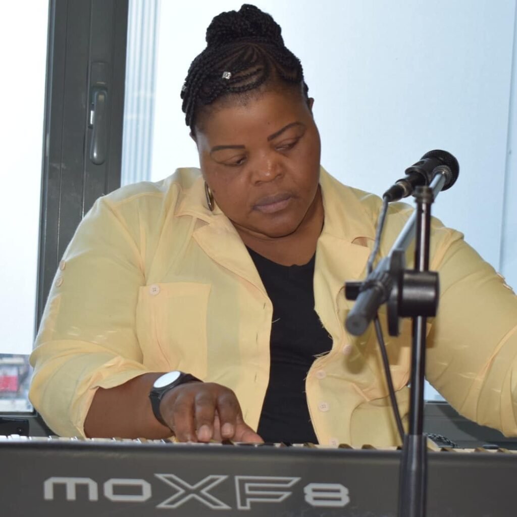 A woman focused intently on playing a Yamaha MOXF8 keyboard during a church service.