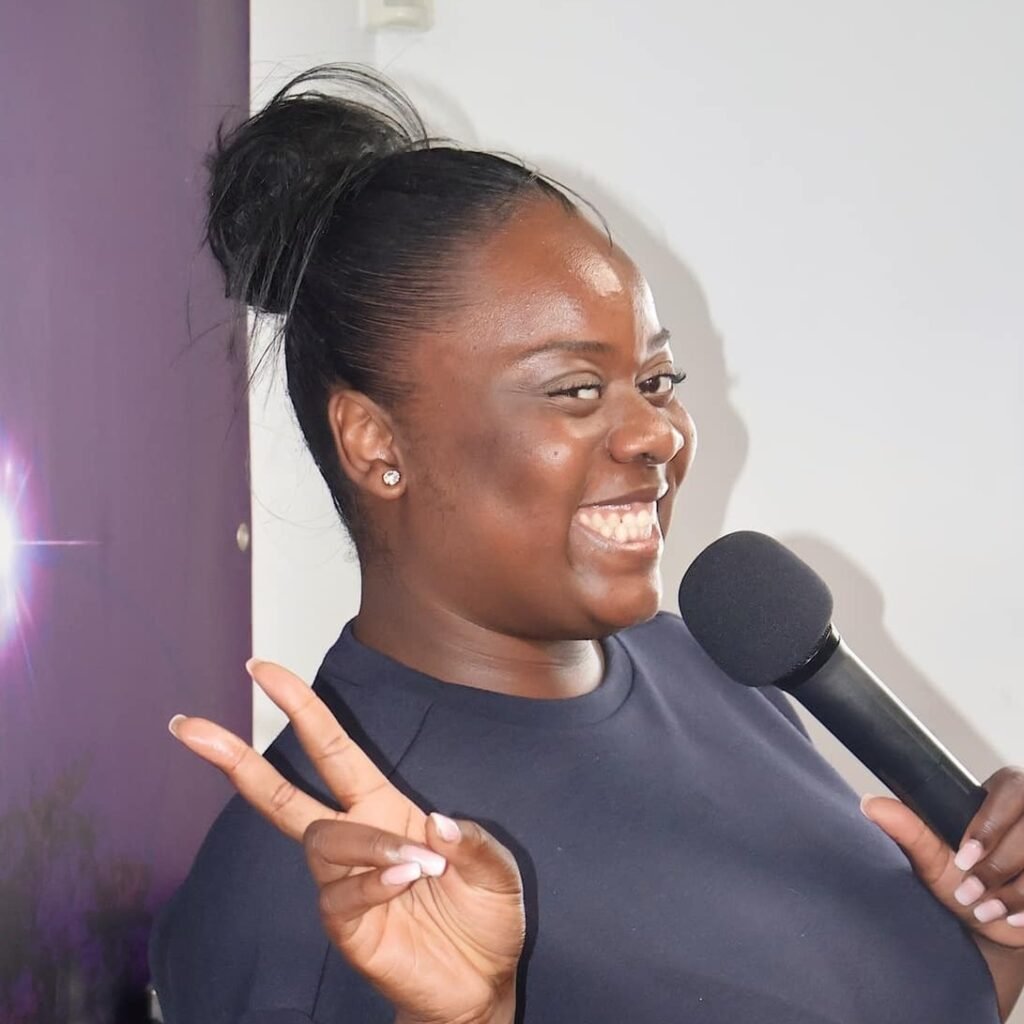 Gracia Mukendi joyfully speaking into a microphone at Église La Bonne Semence.