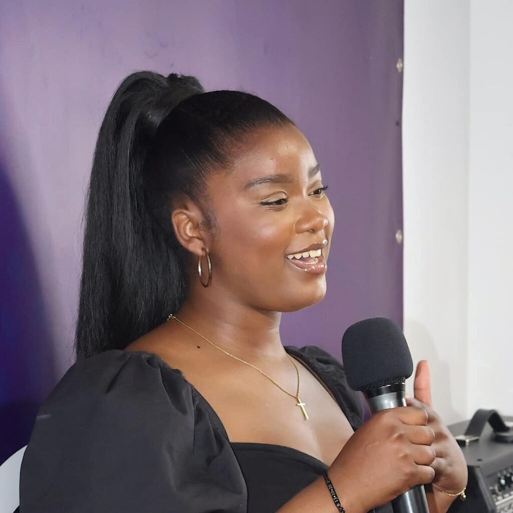 Katia Antonio holding a microphone, expressing joy while speaking