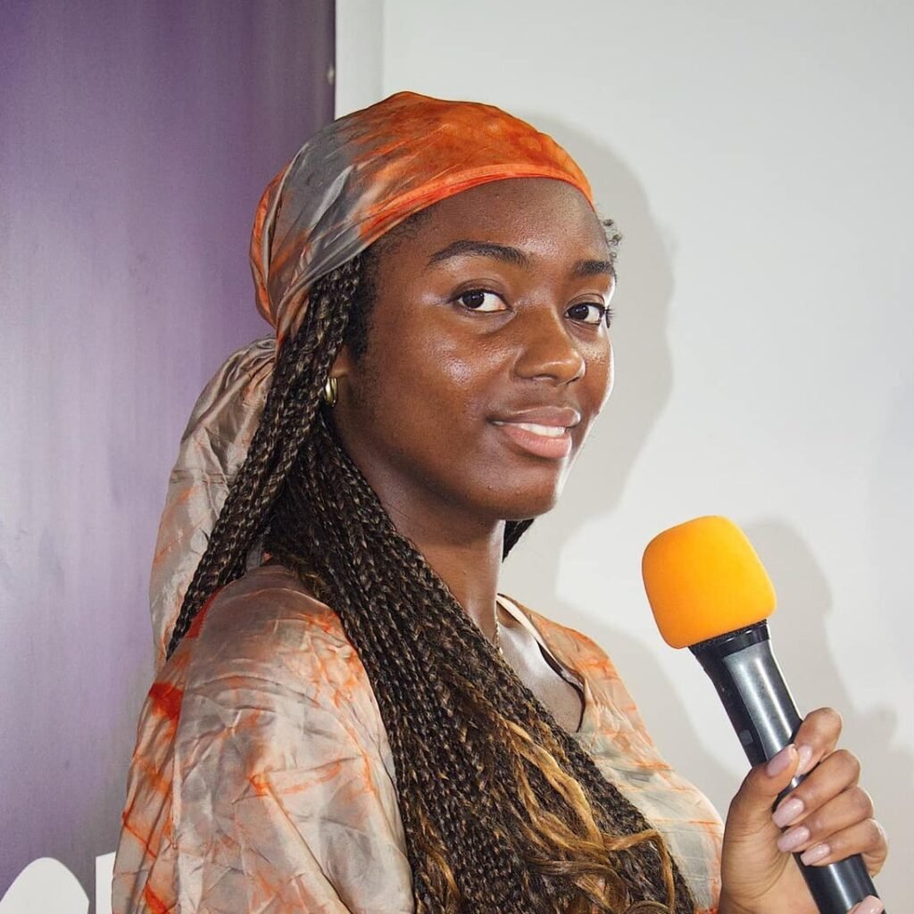 A vibrant portrait of Toyine holding a microphone, ready to speak