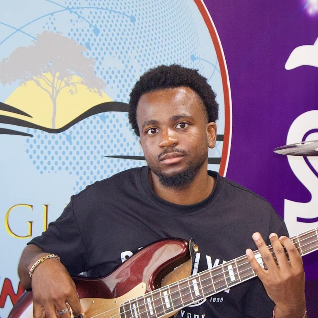 A young man named Cephas, playing a bass guitar, with a church banner in the background.
