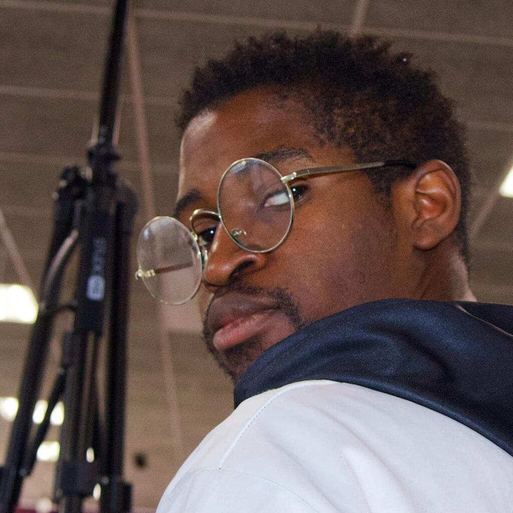 Jonathan looking over his shoulder, wearing stylish round glasses
