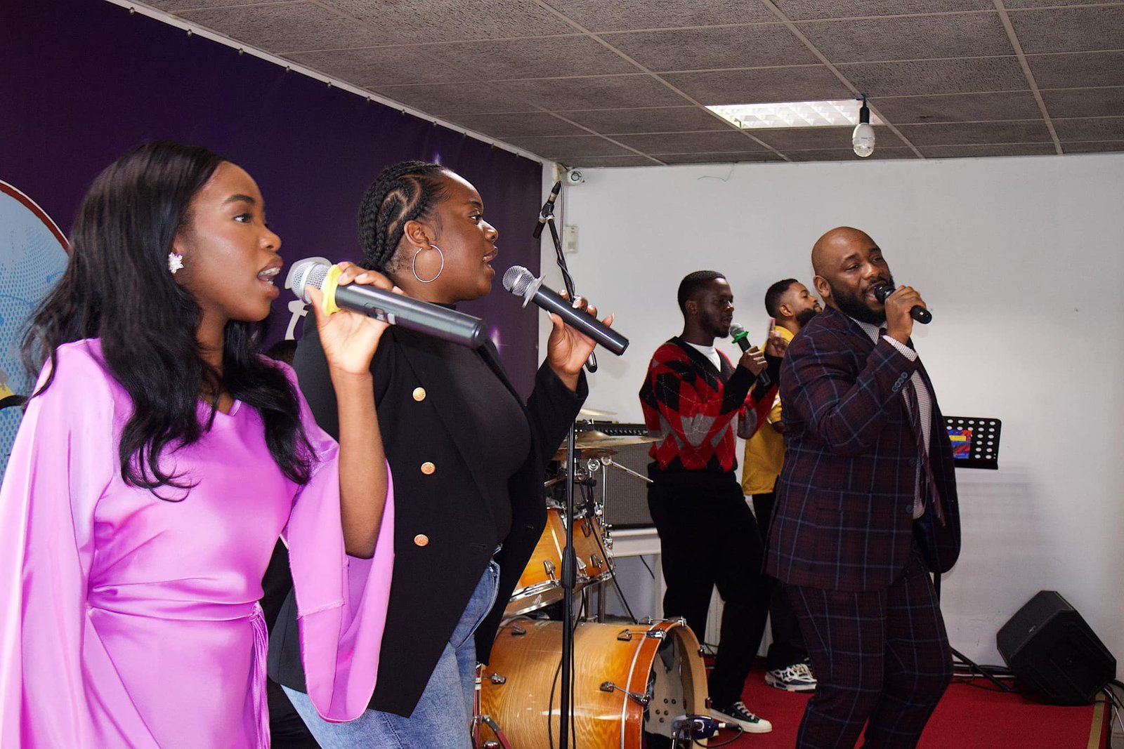 Dynamic church choir performing with passion, featuring vocalists in colorful attire on a purple-themed stage.