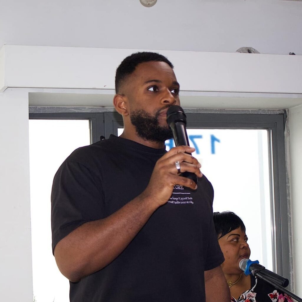 Yves Nikuna speaking into a microphone during a church event
