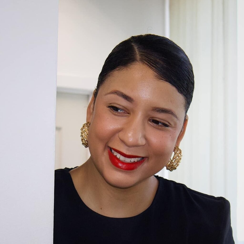 Portrait of Heidy, smiling with red lipstick and elegant earrings.